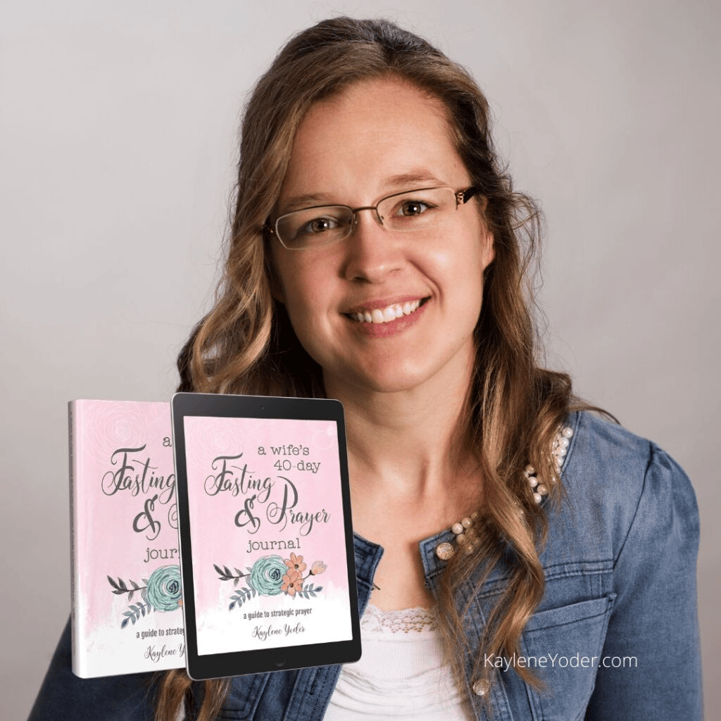 A woman smiling while holding a tablet and a book titled 'a wife's 40-day Fasting & Prayer journal' with floral designs.